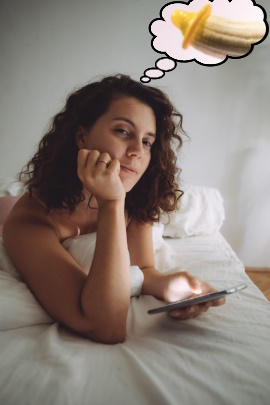 Frau mit Handy liegt auf dem Bett und denkt an Sex