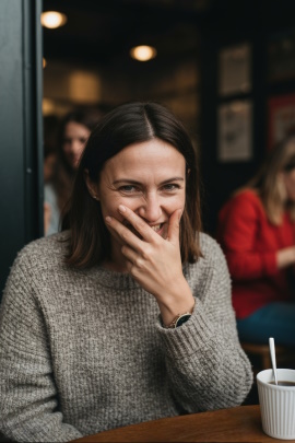 Frau sitzt hämisch lachend im Café