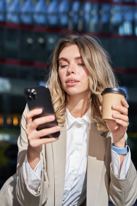 Emotionslose Frau mit Kaffeebecher liest Nachricht am Handy