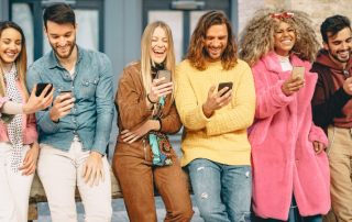 Gruppe fröhlicher Menschen mit Smartphones steht vor einer Wand