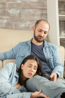 Mann und Frau sitzen gelangweilt zuhause auf dem Sofa