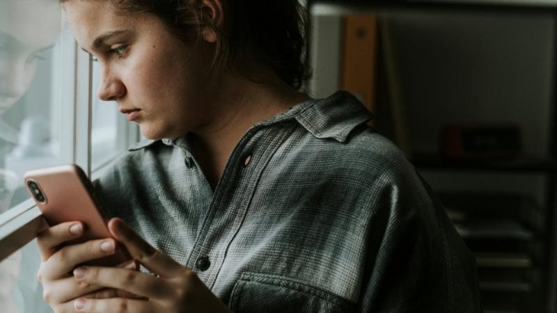 Frau schaut traurig aus dem Fenster, weil Mann sich nicht meldet