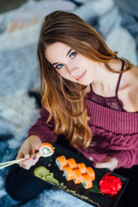 Frau isst Sushi und schaut in die Kamera