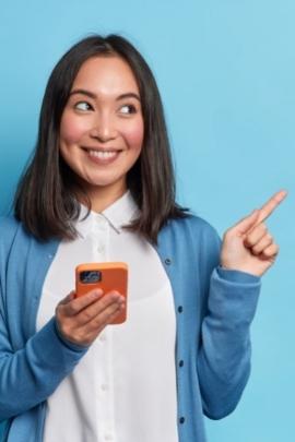 Frau hat ihr Handy in der Hand und zeigt nach rechts