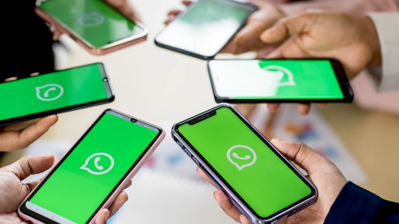 Menschen halten Smartphones mit WhatsApp-Logo im Display