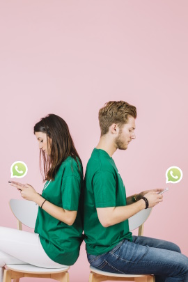 Paar sitzt mit Rücken zueinander und schaut am Handy in WhatsApp