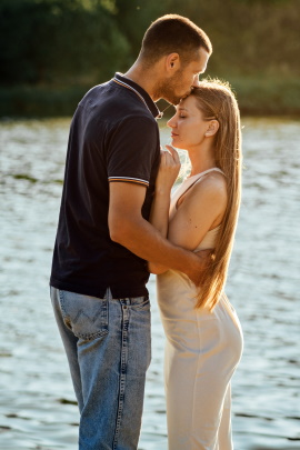 Mann küsst Frau auf die Stirn am Ufer