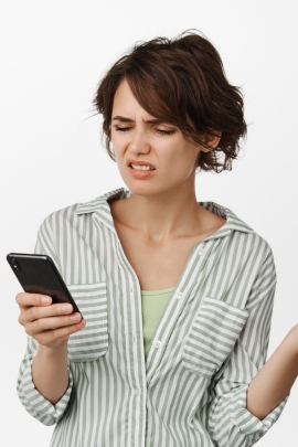 Verliebte Frau schaut genervt auf ihr Handy, weil sie Missverständnis mit Mann hat