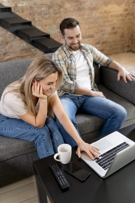 Mann und Frau sitzen im Wohnzimmer vor dem Laptop